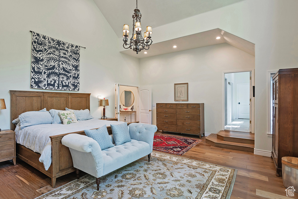 Bedroom with high vaulted ceiling, wood finished floors, a chandelier, recessed lighting, and baseboards