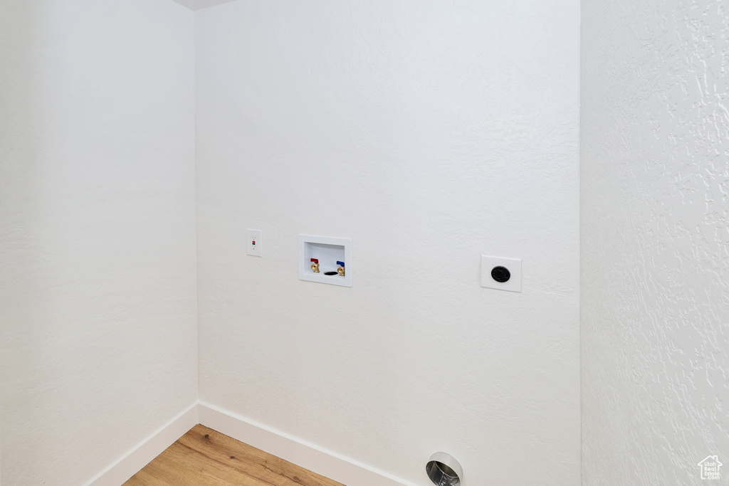 Laundry area with hookup for an electric dryer, baseboards, light wood-type flooring, and washer hookup