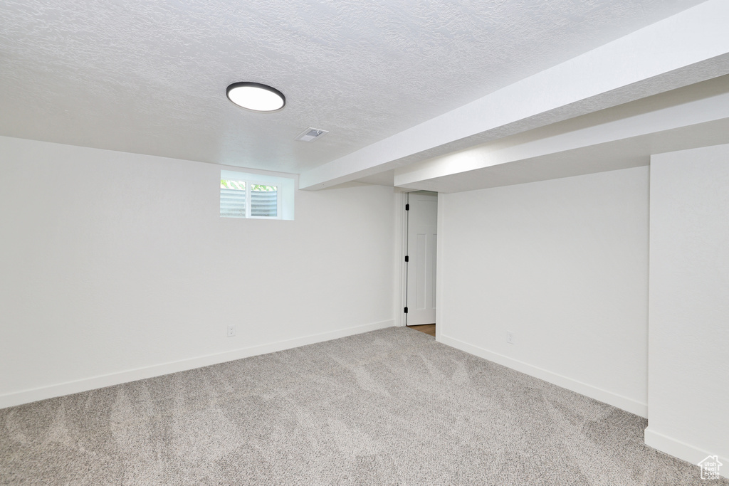 Basement with baseboards, carpet floors, and a textured ceiling