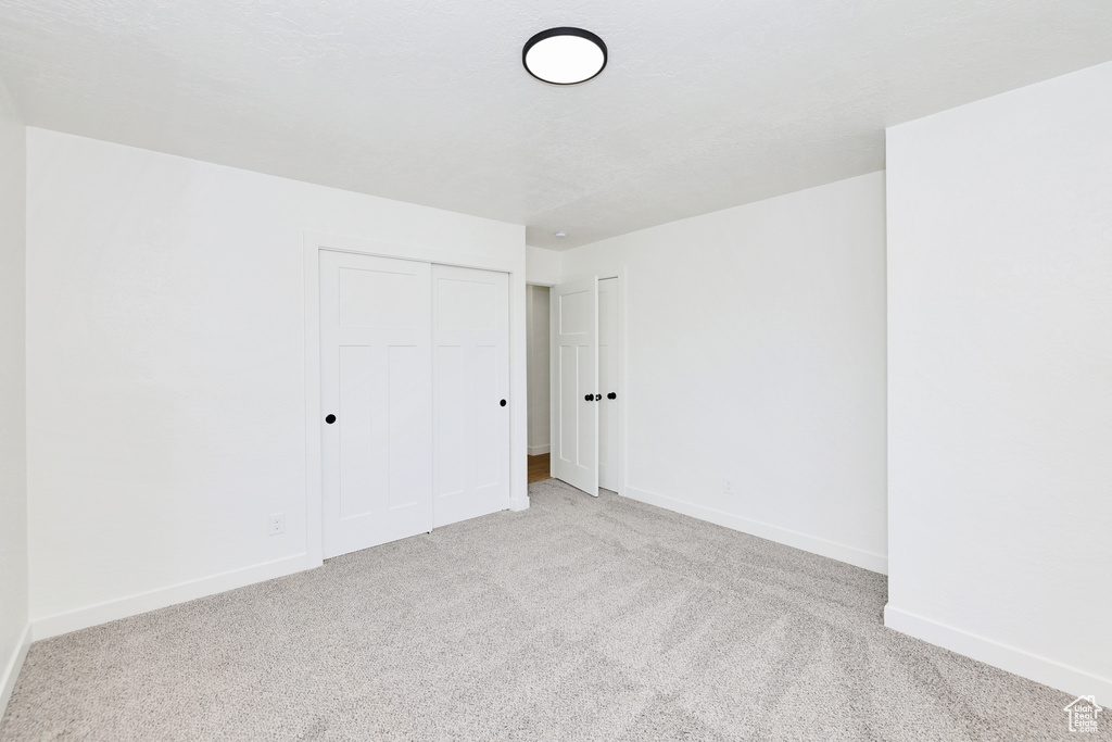 Unfurnished bedroom with carpet floors, baseboards, and a closet