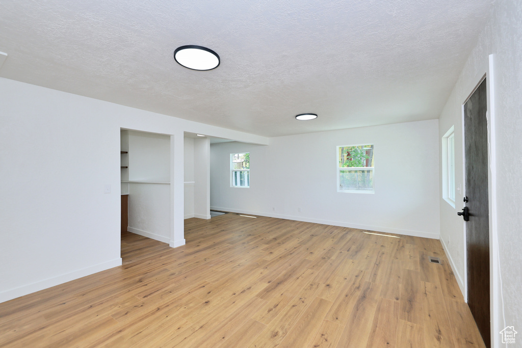 Unfurnished bedroom with a textured ceiling, light wood-type flooring, and baseboards