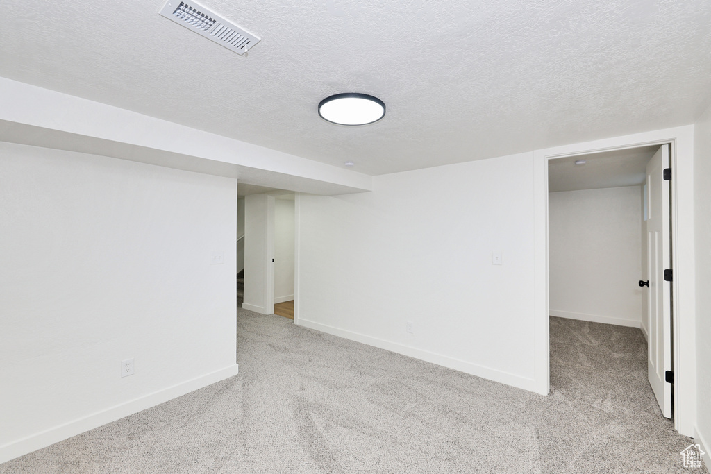 Finished basement with carpet floors, baseboards, and a textured ceiling