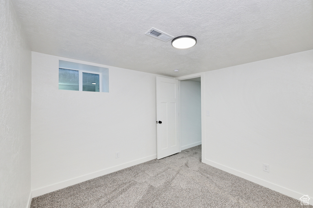Finished below grade area featuring carpet floors, baseboards, and a textured ceiling