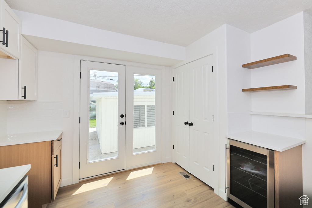 Doorway to outside featuring beverage cooler and light wood finished floors