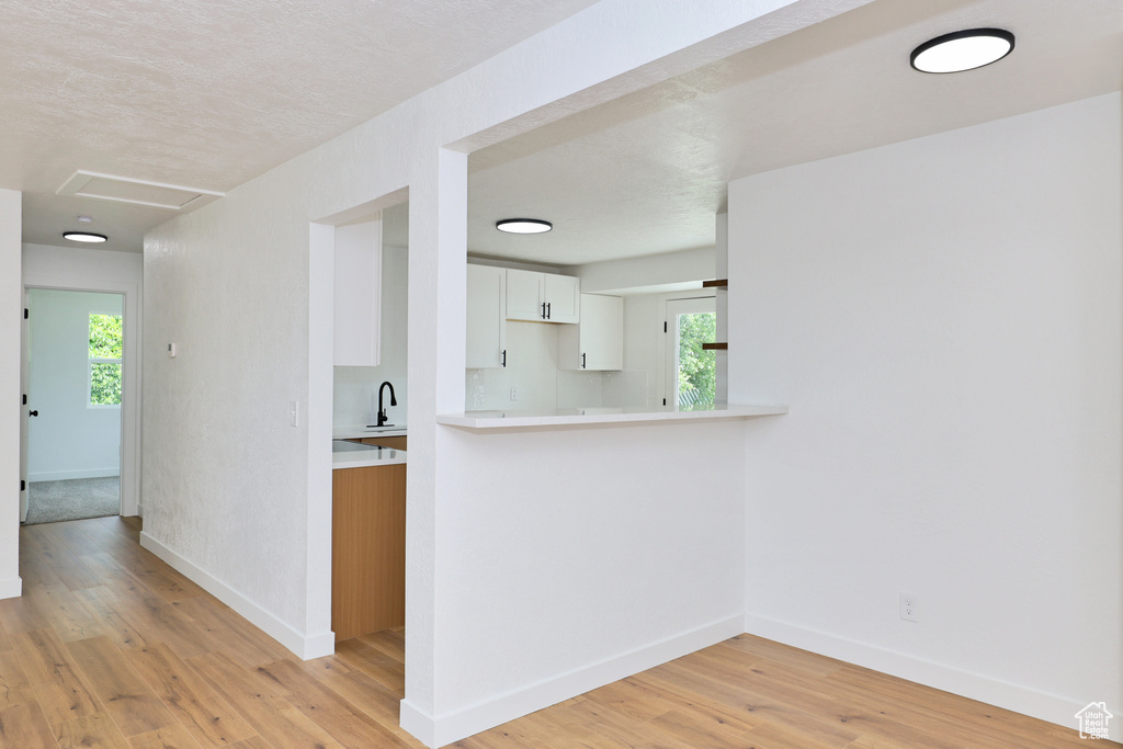 Hallway with baseboards, light wood finished floors, and healthy amount of natural light