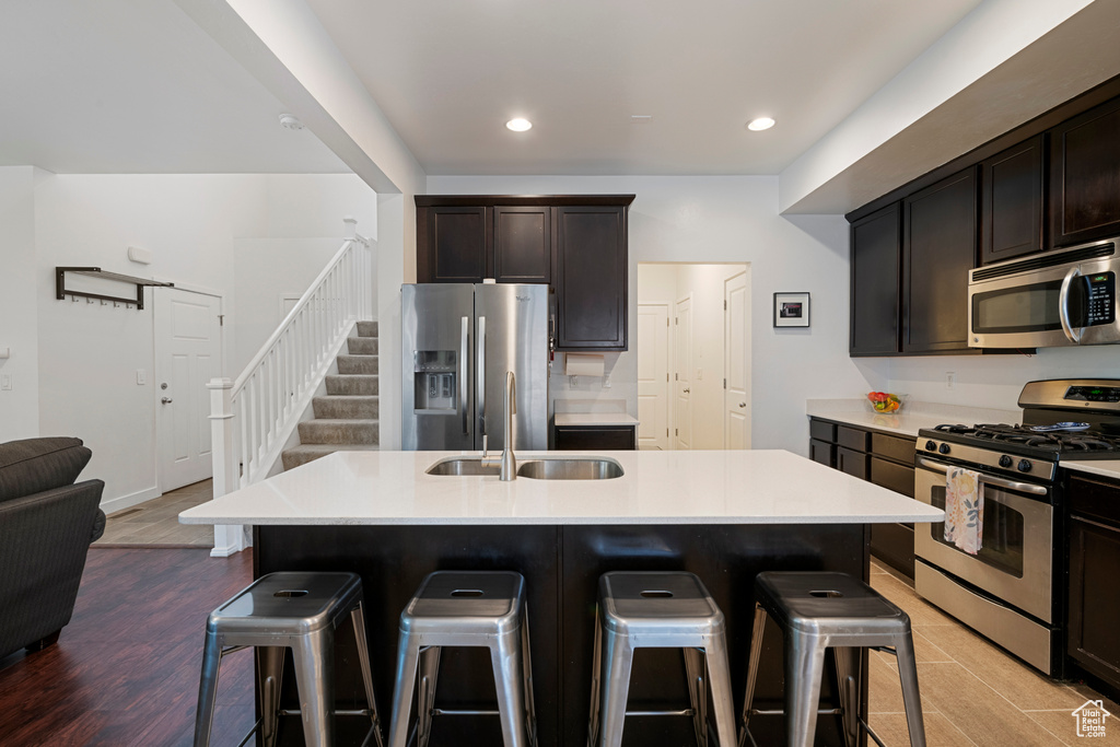 Kitchen featuring appliances with stainless steel finishes, a kitchen breakfast bar, a sink, recessed lighting, and light countertops