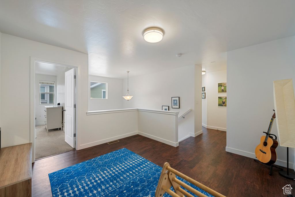 Hallway with wood finished floors, an upstairs landing, and baseboards