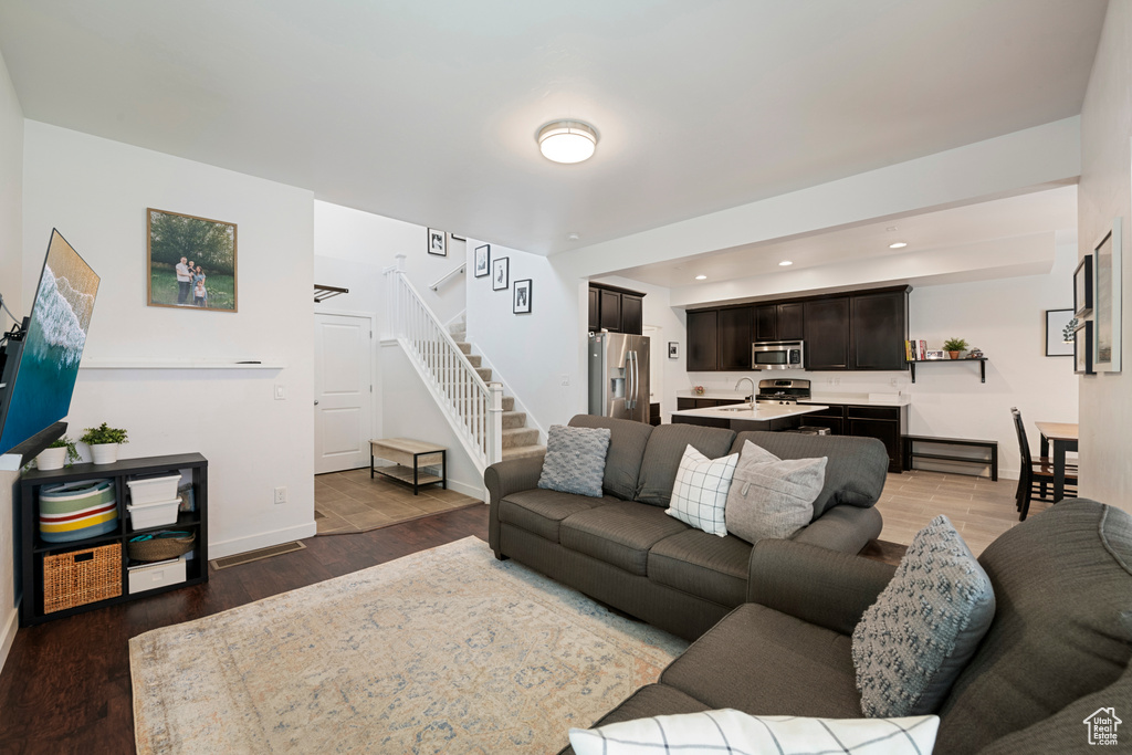 Living room featuring stairs, baseboards, wood finished floors, and recessed lighting