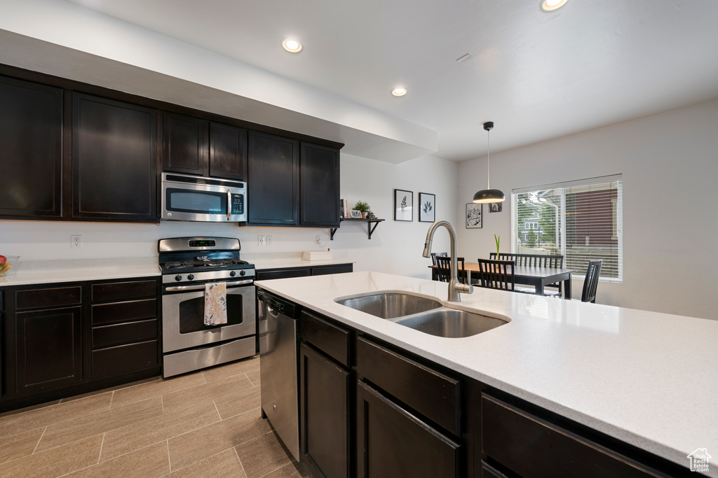 Kitchen with stainless steel appliances, a sink, light countertops, pendant lighting, and recessed lighting