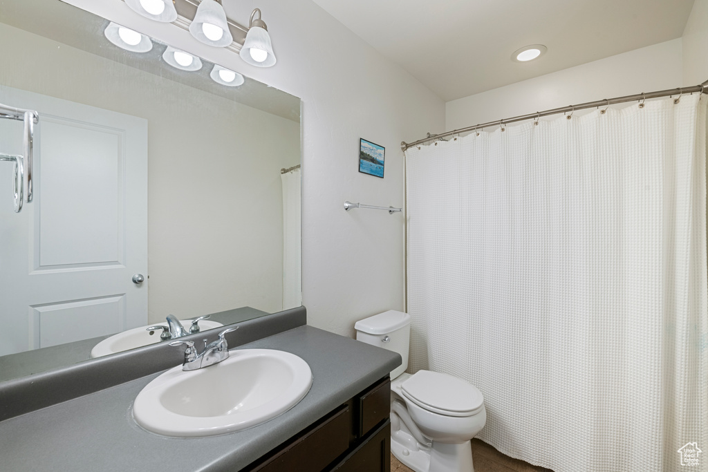 Full bath with toilet, vanity, and a shower with shower curtain