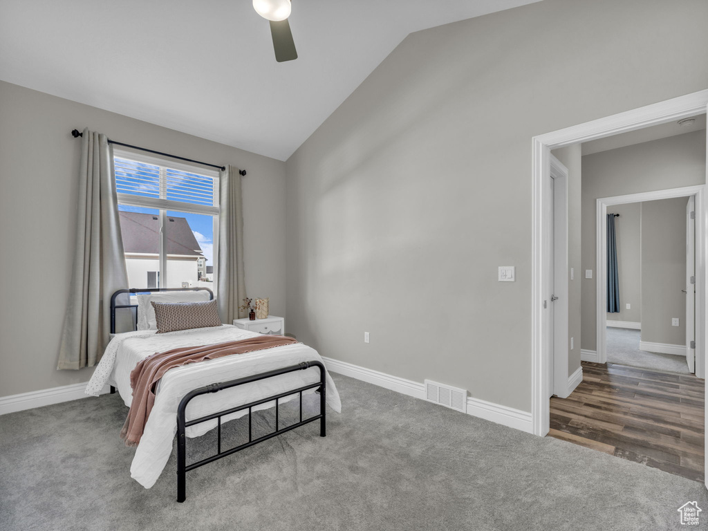 Carpeted bedroom featuring vaulted ceiling, baseboards, and a ceiling fan