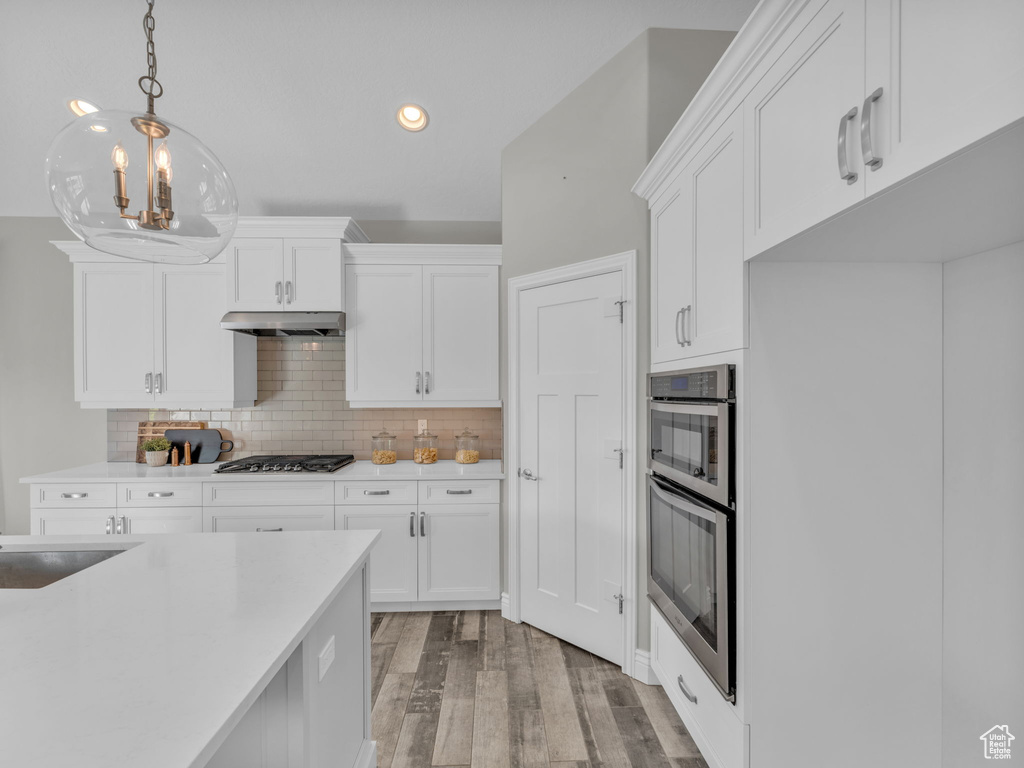 Kitchen featuring appliances with stainless steel finishes, light wood-type flooring, white cabinetry, decorative light fixtures, and recessed lighting