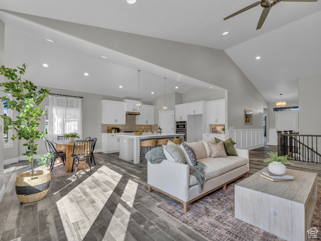 Living area featuring high vaulted ceiling, ceiling fan, wood finished floors, recessed lighting, and a chandelier
