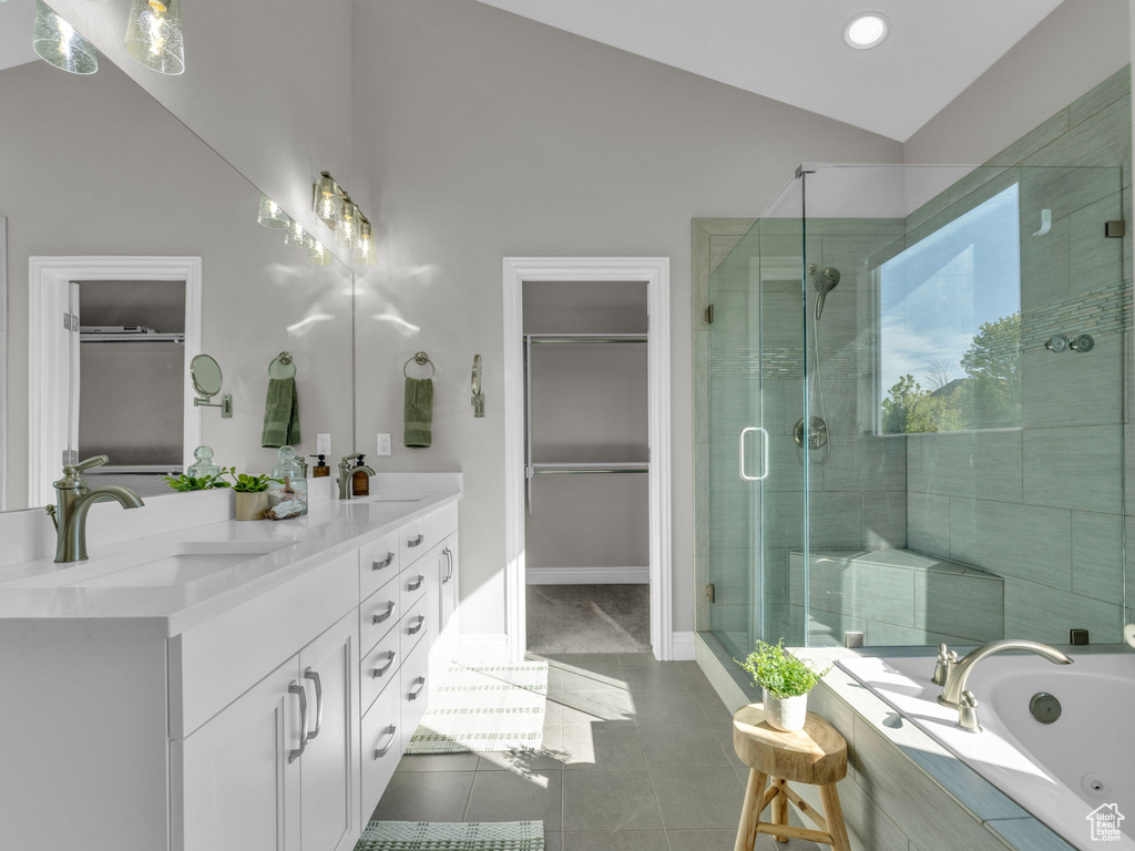 Bathroom featuring a stall shower, double vanity, tile patterned floors, a spacious closet, and vaulted ceiling