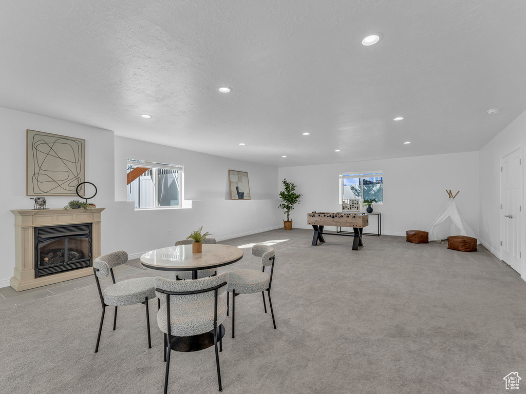 Dining space with recessed lighting, plenty of natural light, a glass covered fireplace, light colored carpet, and baseboards