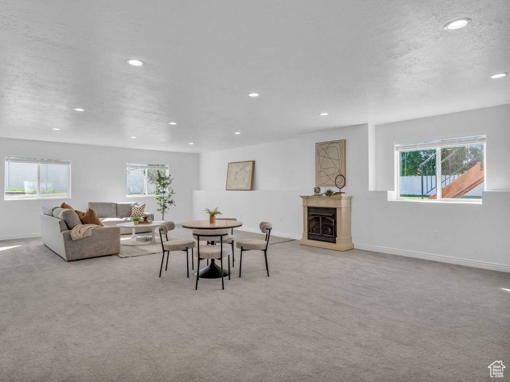 Dining room featuring a fireplace with raised hearth, light colored carpet, recessed lighting, and healthy amount of natural light