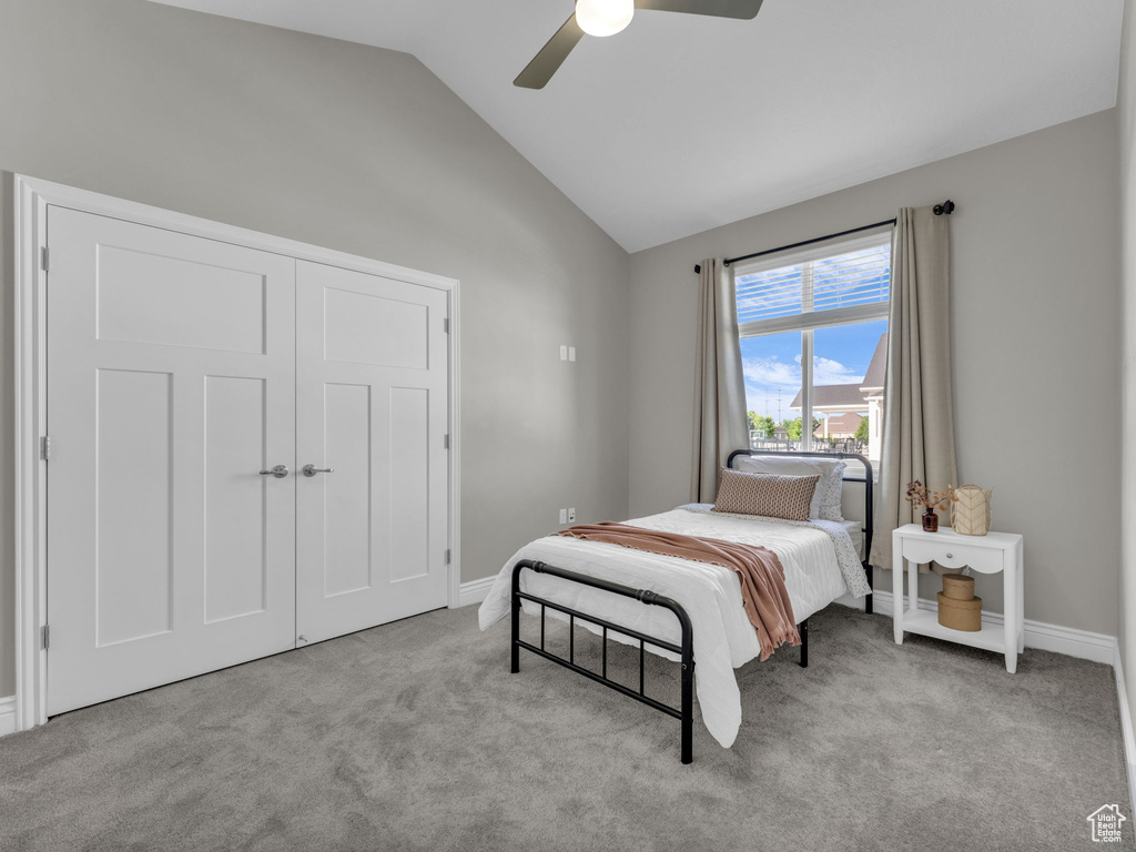 Bedroom featuring lofted ceiling, carpet floors, baseboards, a ceiling fan, and a closet