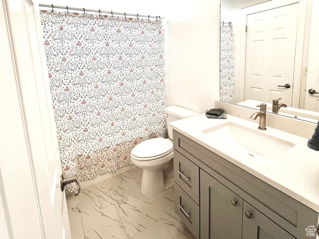 Full bath featuring vanity, marble finish floors, toilet, a textured ceiling, and a shower with shower curtain