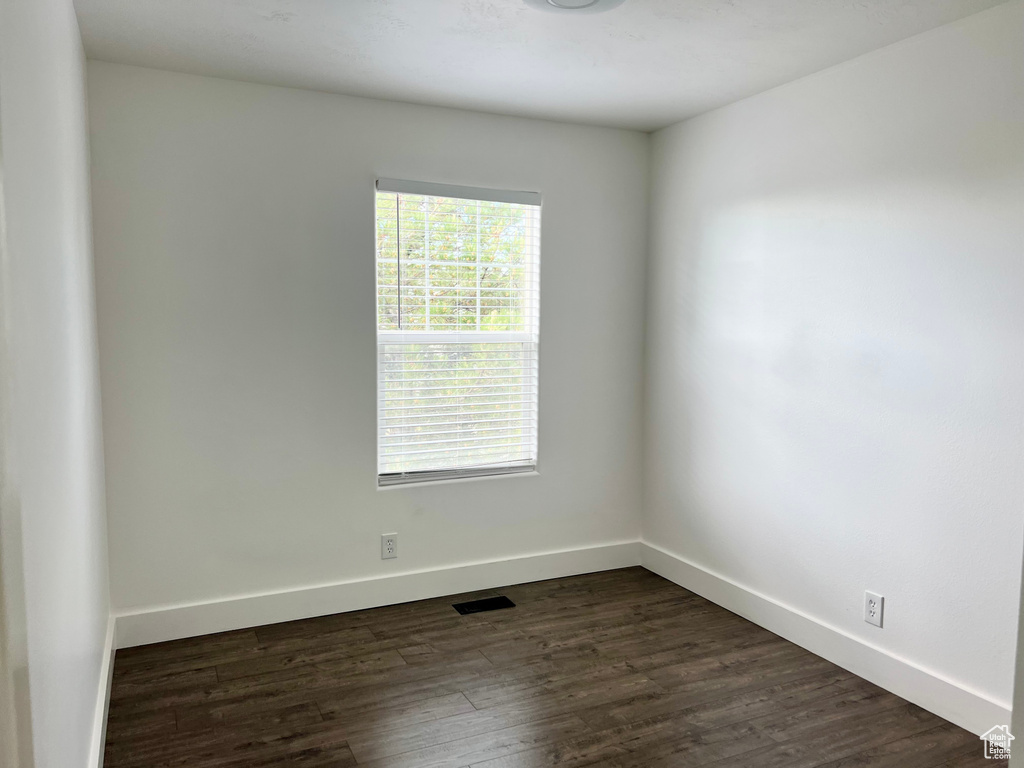 Spare room featuring plenty of natural light, dark wood-type flooring, and baseboards