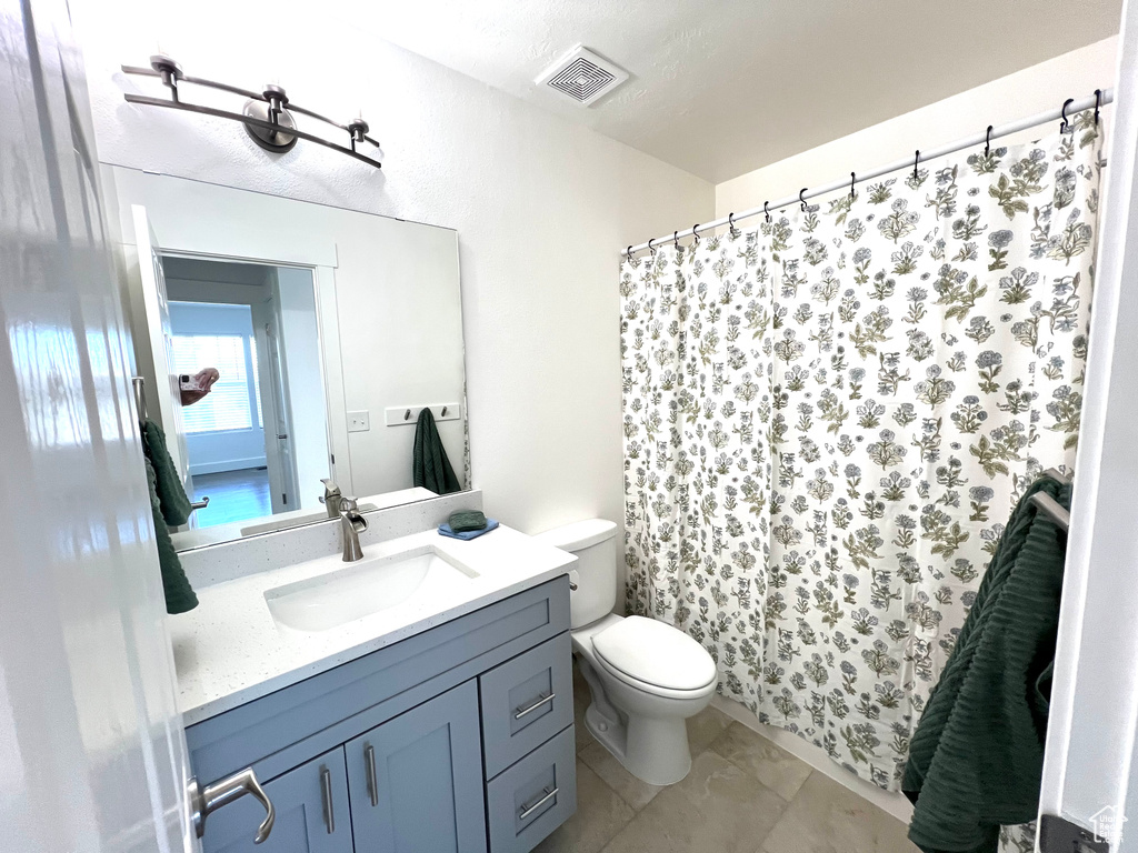 Bathroom with vanity, toilet, and curtained shower