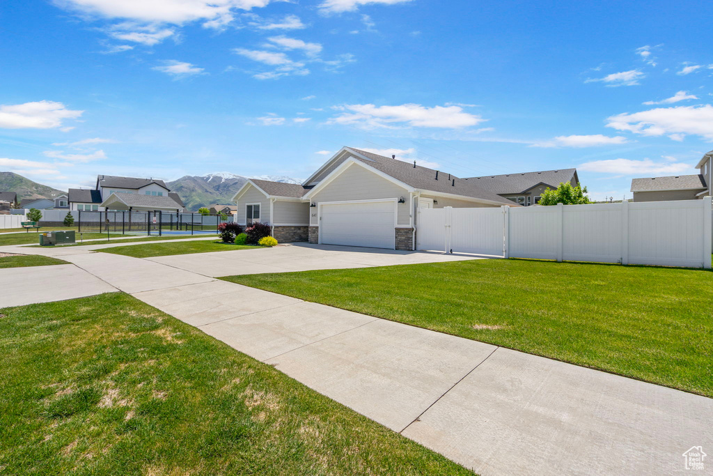 View of front of home featuring a gate, driveway, an attached garage, stone siding, and a mountain view