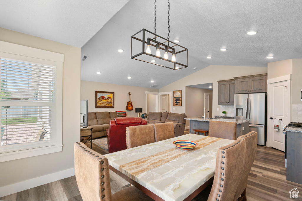 Dining space with dark wood-style floors, vaulted ceiling, and baseboards