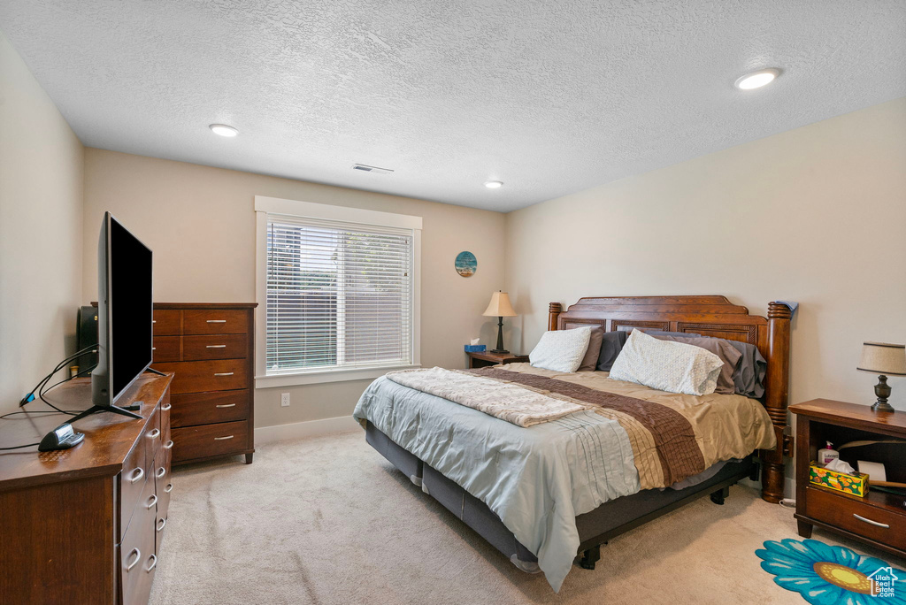 Bedroom featuring light colored carpet, a textured ceiling, recessed lighting, and baseboards