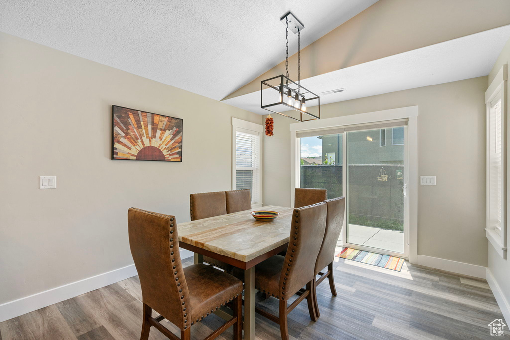 Dining area featuring lofted ceiling, wood finished floors, baseboards, and a textured ceiling