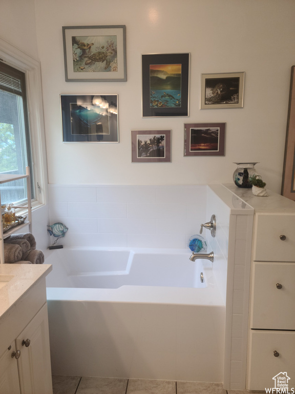 Full bath featuring vanity, a bath, and tile patterned flooring