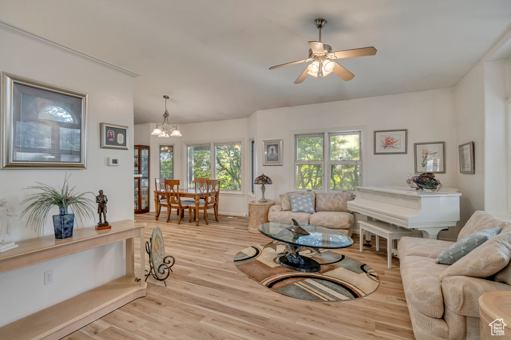 Living room with a chandelier, light wood finished floors, and a ceiling fan
