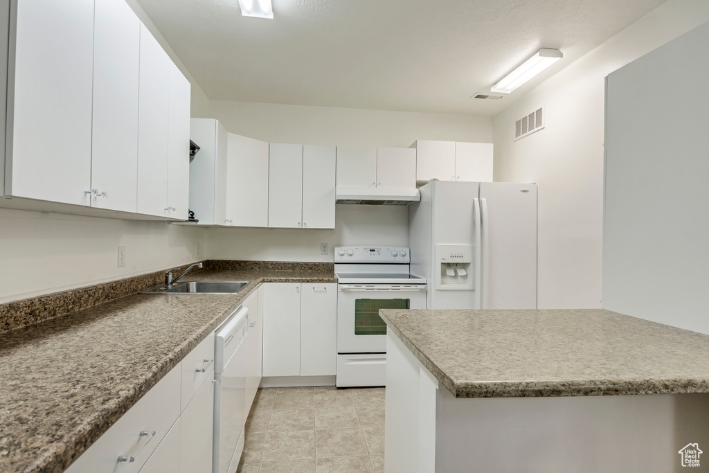 Kitchen featuring white appliances, a sink, under cabinet range hood, white cabinetry, and light tile patterned floors