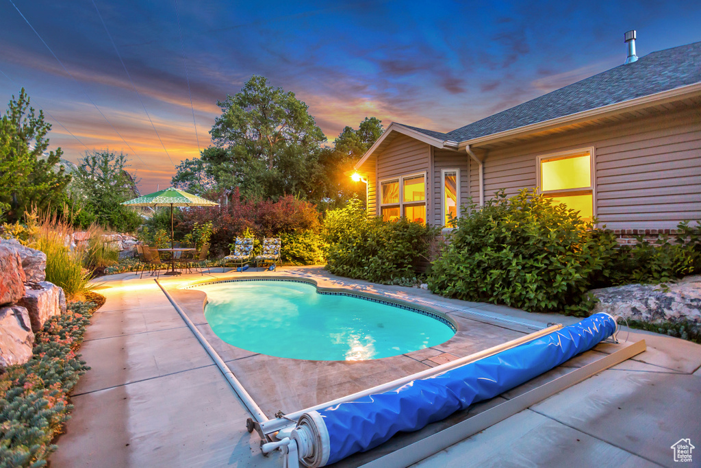 Pool at dusk featuring a patio area and a covered pool