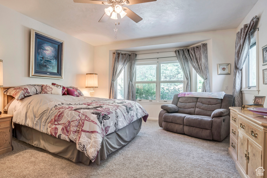 Bedroom with light carpet, multiple windows, and a ceiling fan
