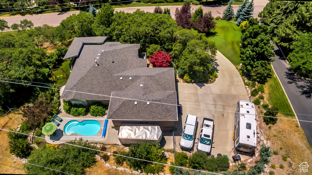 Aerial view of property and surrounding area featuring a pool area, a tree filled landscape, and property parcel outlined