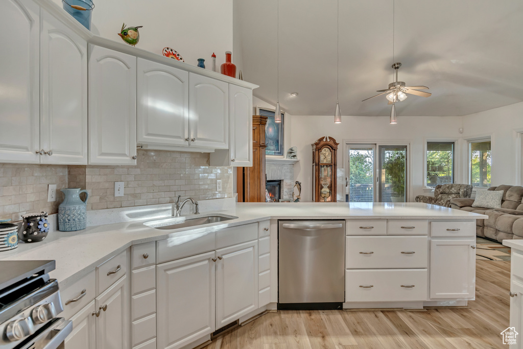 Kitchen with appliances with stainless steel finishes, a sink, open floor plan, light wood-type flooring, and lofted ceiling