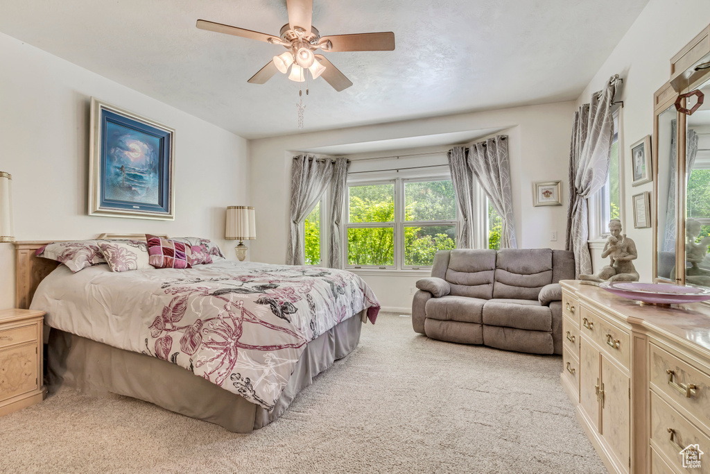 Carpeted bedroom featuring multiple windows and ceiling fan