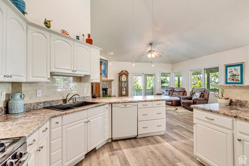 Kitchen featuring white dishwasher, a sink, ceiling fan, light wood finished floors, and tasteful backsplash