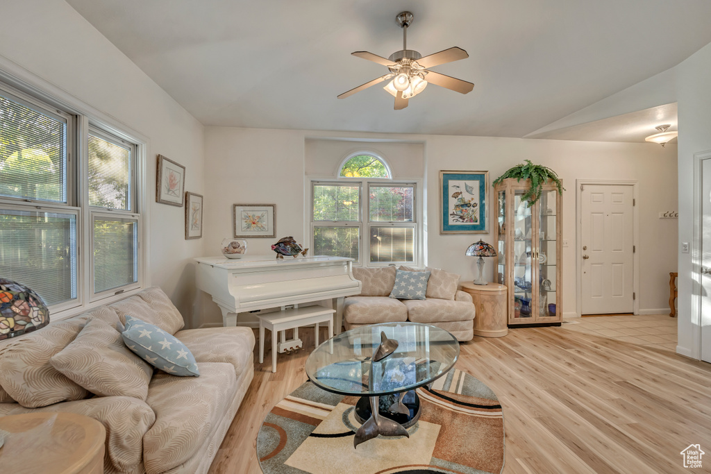 Living room with light wood-type flooring, a ceiling fan, and vaulted ceiling