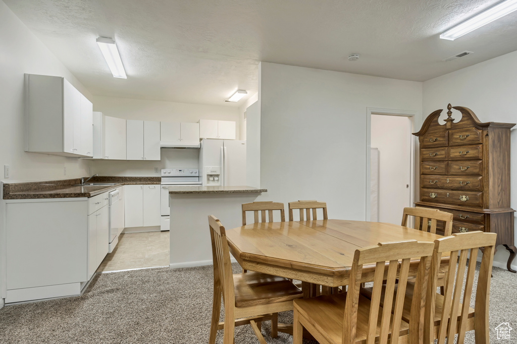 Dining room with light colored carpet and a textured ceiling