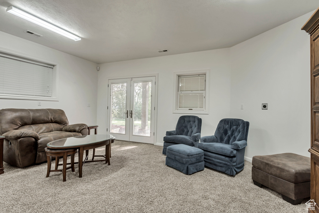 Living area with french doors, light colored carpet, and baseboards