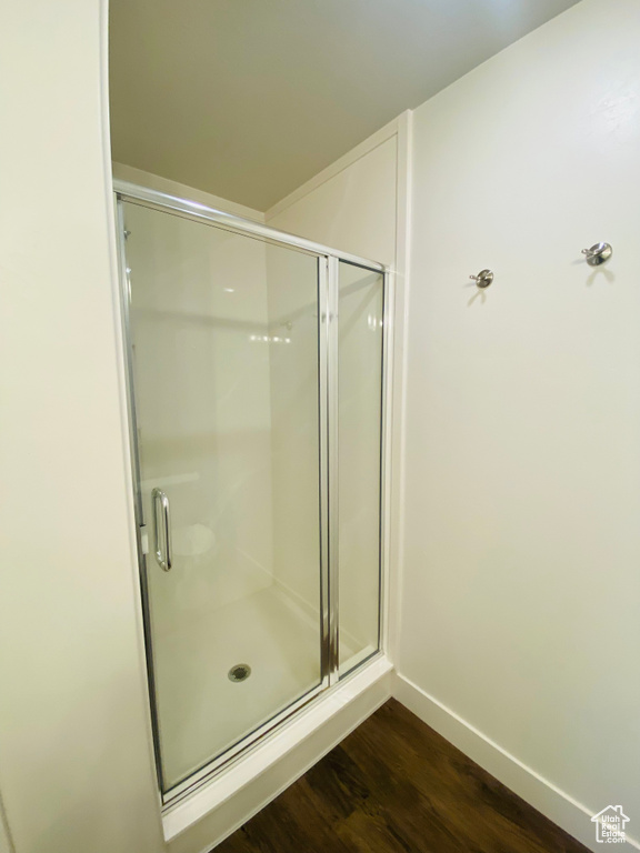 Full bathroom with wood finished floors, a stall shower, and baseboards