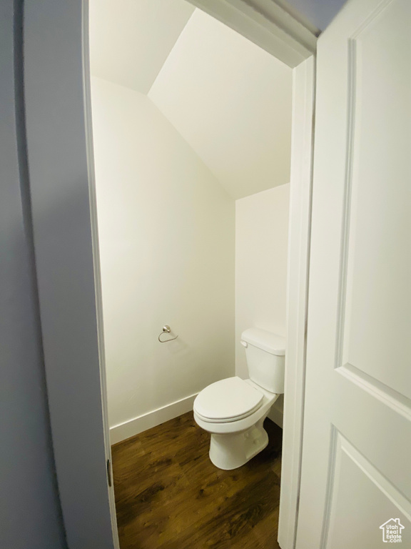 Bathroom with wood finished floors, toilet, and lofted ceiling