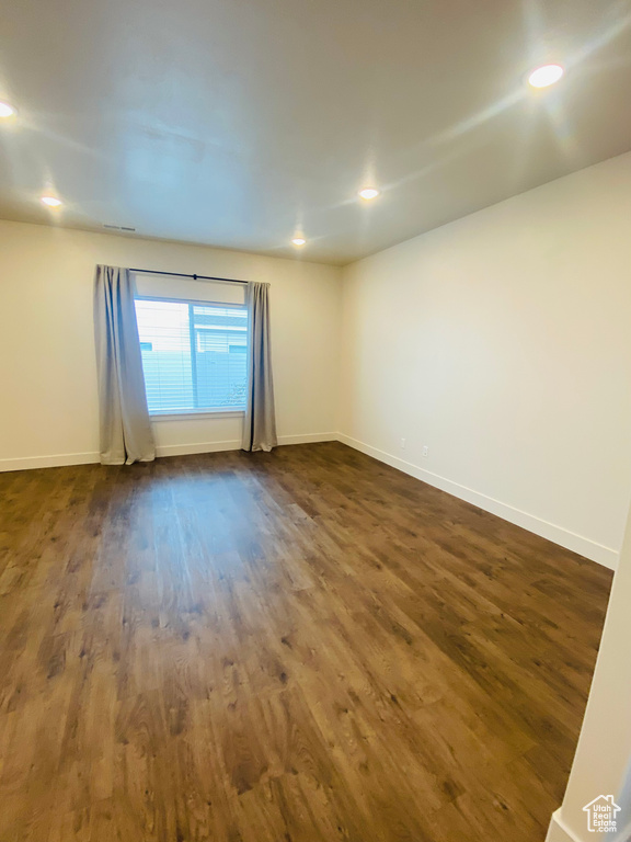 Unfurnished room featuring dark wood-style floors, baseboards, and recessed lighting