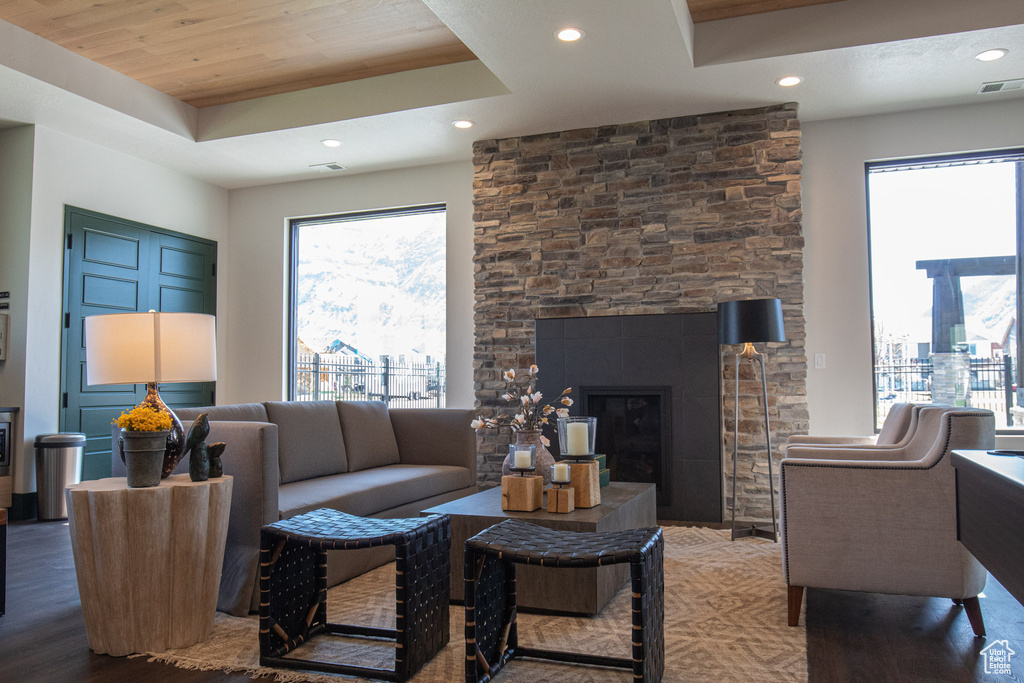 Living area with a tray ceiling, recessed lighting, a large fireplace, and wood finished floors
