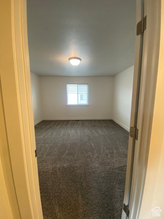 Spare room with dark colored carpet and baseboards