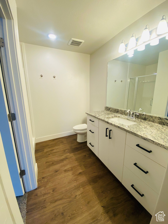 Full bath with toilet, vanity, a shower stall, wood finished floors, and recessed lighting