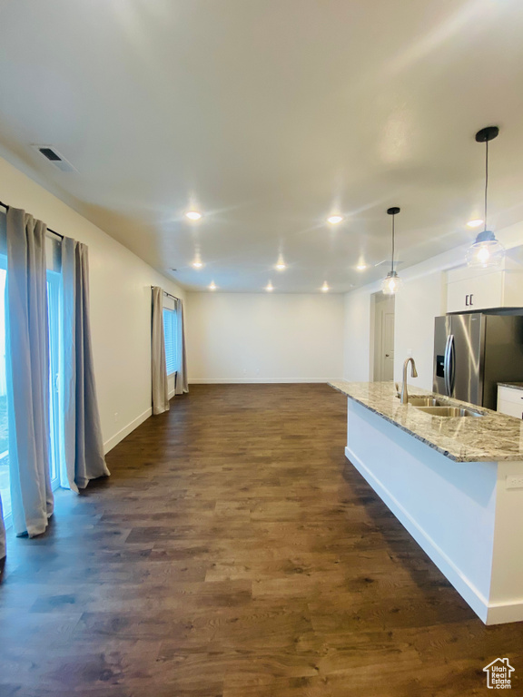 Unfurnished living room featuring a sink, baseboards, and dark wood-style floors