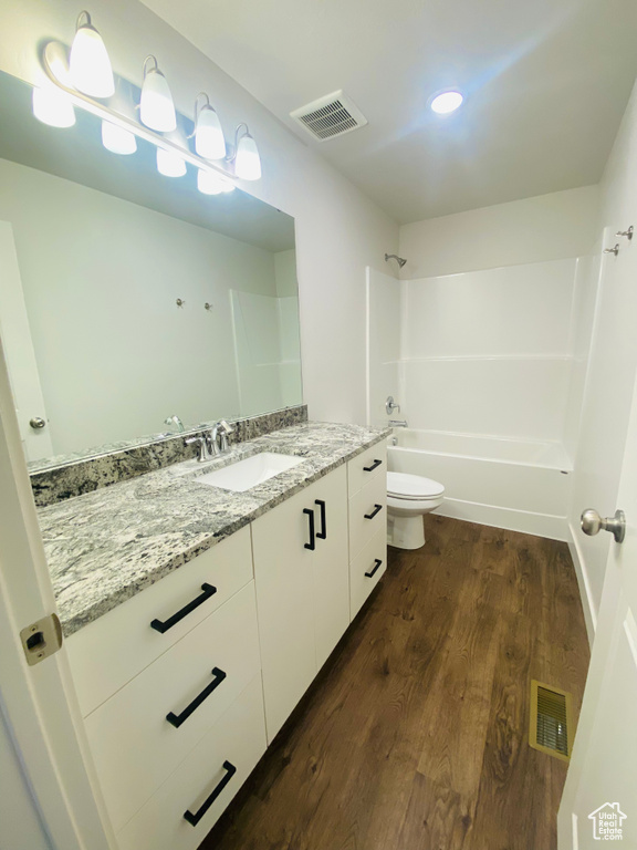 Full bath with vanity, toilet, wood finished floors, and tub / shower combination