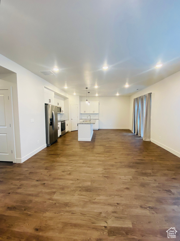 Unfurnished living room featuring baseboards, a sink, dark wood-type flooring, and recessed lighting