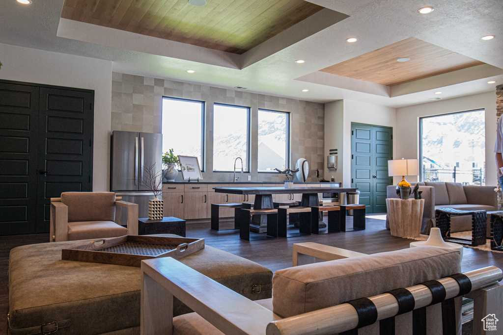 Living room with a raised ceiling, dark wood-style flooring, and recessed lighting